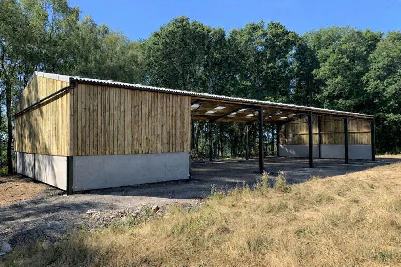 Agricultural storage building with timber cladding and open lean-to