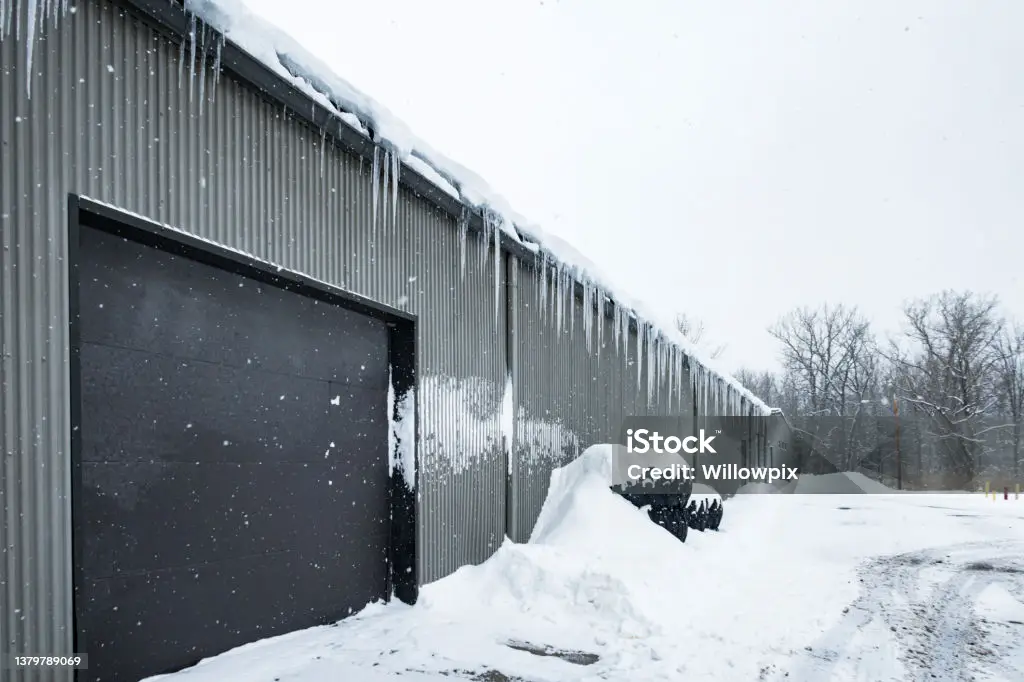 Steel clad building with icicles in winter snow